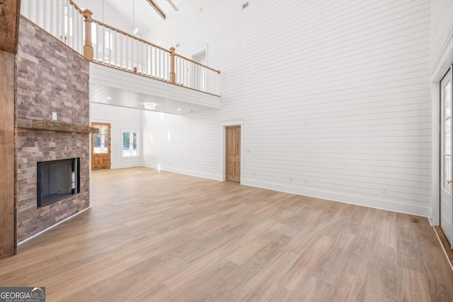 unfurnished living room with hardwood / wood-style floors, a high ceiling, and a multi sided fireplace