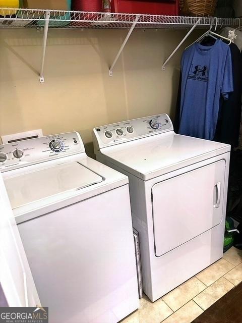 clothes washing area featuring tile patterned flooring and separate washer and dryer