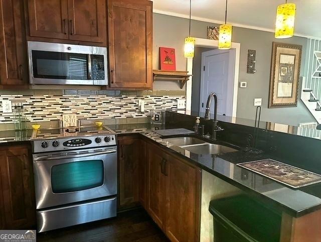 kitchen featuring appliances with stainless steel finishes, decorative light fixtures, sink, and decorative backsplash