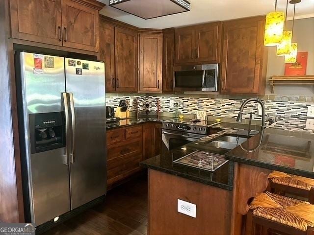 kitchen featuring stainless steel appliances, hanging light fixtures, backsplash, and dark hardwood / wood-style flooring