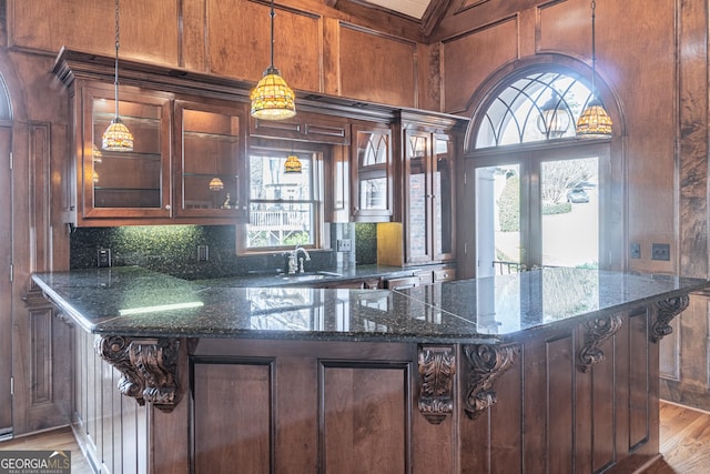 kitchen featuring pendant lighting, decorative backsplash, dark stone countertops, and light wood-type flooring