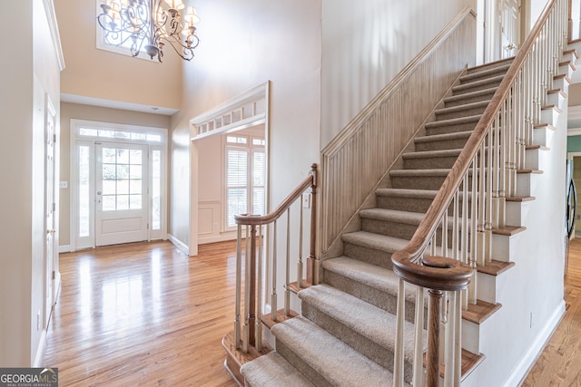 foyer with a towering ceiling, light hardwood / wood-style flooring, and a notable chandelier