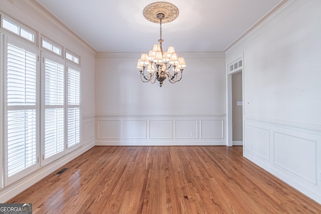 empty room with plenty of natural light, a chandelier, and hardwood / wood-style floors