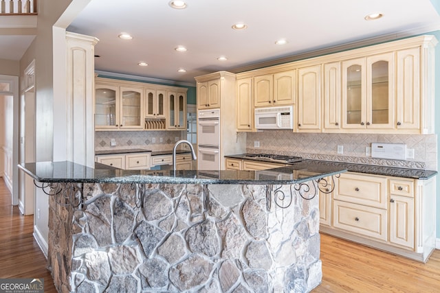 kitchen featuring a large island with sink, dark stone countertops, a kitchen breakfast bar, and white appliances