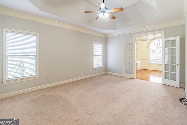 carpeted spare room with a raised ceiling, crown molding, ceiling fan, and french doors