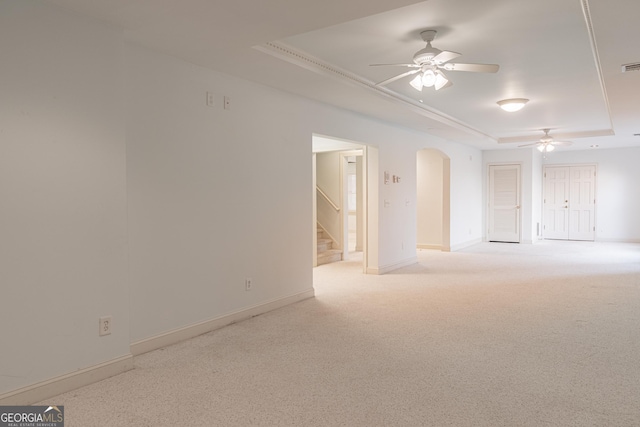 carpeted empty room with a tray ceiling and ceiling fan