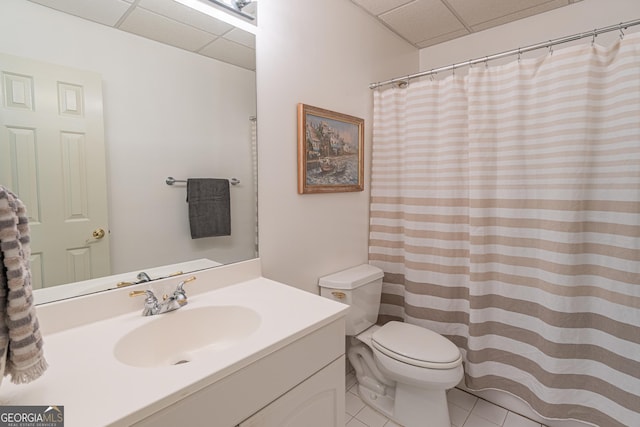 bathroom featuring a drop ceiling, vanity, tile patterned floors, and toilet