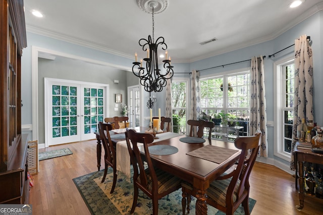 dining room featuring crown molding, a notable chandelier, light wood-type flooring, and french doors