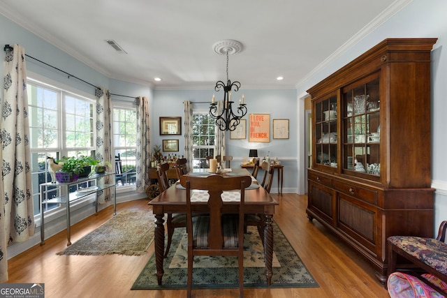 dining room featuring ornamental molding, a chandelier, and light hardwood / wood-style floors