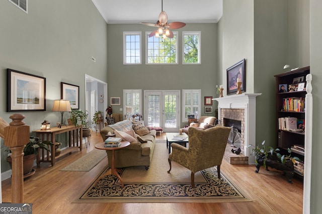 living room with crown molding, light wood-type flooring, ceiling fan, and a fireplace