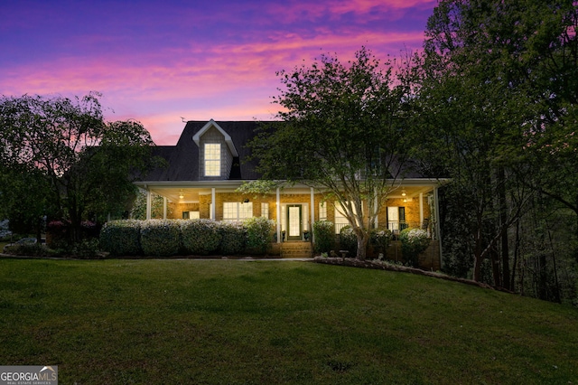 cape cod home featuring a porch and a yard