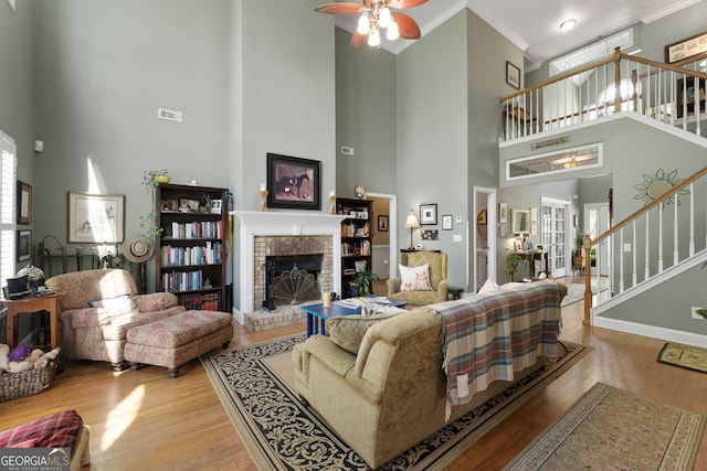 living room with a brick fireplace, crown molding, plenty of natural light, and light hardwood / wood-style floors