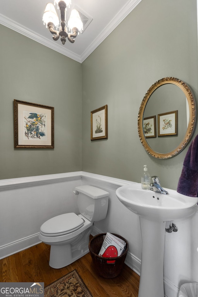 bathroom with crown molding, hardwood / wood-style floors, a notable chandelier, and toilet