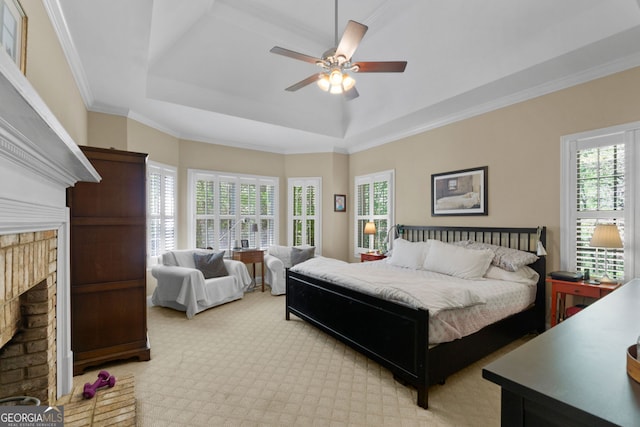 carpeted bedroom with crown molding, a fireplace, a raised ceiling, and multiple windows