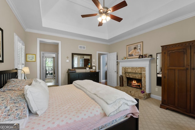 bedroom with light carpet, a brick fireplace, a raised ceiling, and ceiling fan