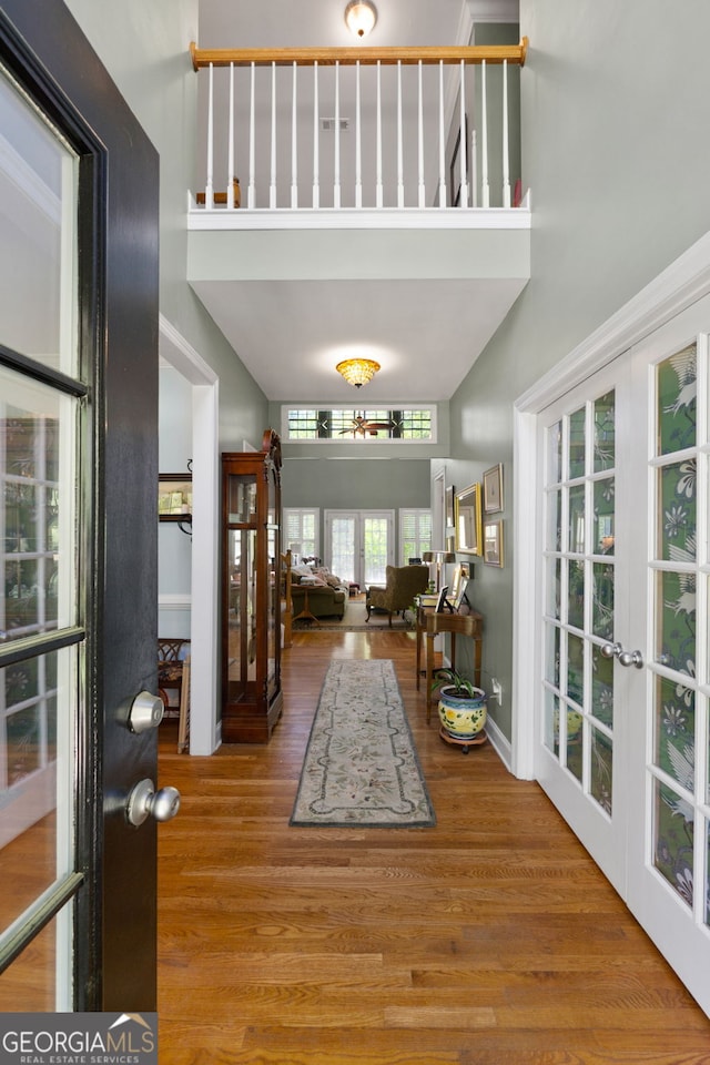 foyer with a towering ceiling, wood-type flooring, and french doors