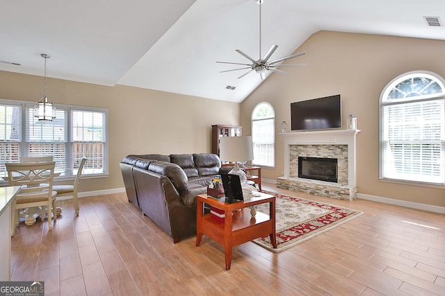 living room with high vaulted ceiling, a fireplace, light hardwood / wood-style floors, and ceiling fan