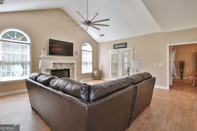 living room with light hardwood / wood-style flooring, a fireplace, high vaulted ceiling, and ceiling fan