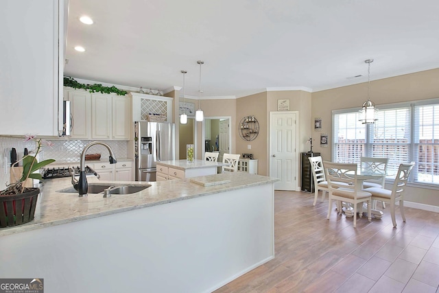 kitchen featuring sink, hanging light fixtures, stainless steel appliances, tasteful backsplash, and light stone countertops