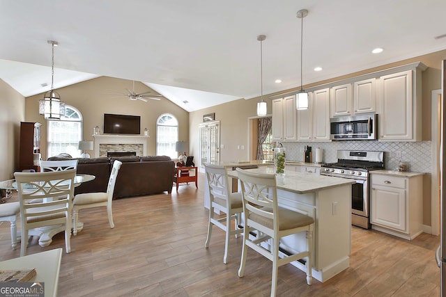 kitchen featuring a kitchen island, a breakfast bar, hanging light fixtures, stainless steel appliances, and light stone countertops