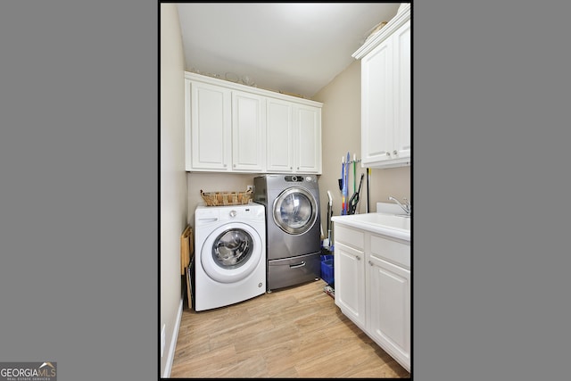 washroom featuring cabinets, sink, washer and dryer, and light wood-type flooring