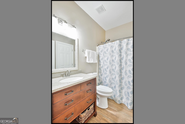 bathroom with hardwood / wood-style flooring, vanity, walk in shower, and toilet