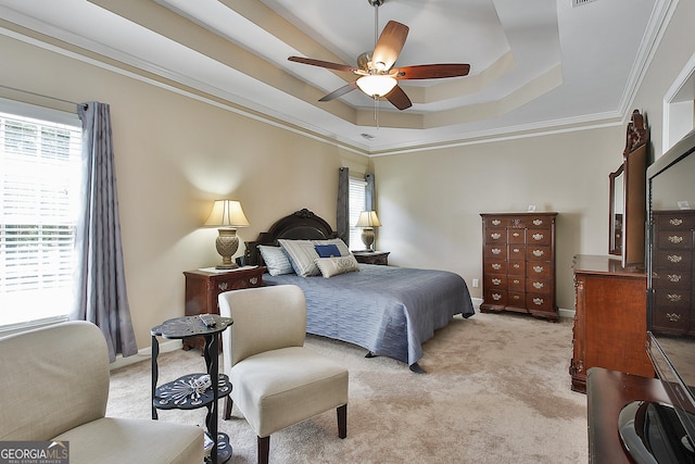 bedroom featuring ceiling fan, light colored carpet, ornamental molding, and a tray ceiling