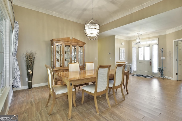 dining space with an inviting chandelier, ornamental molding, and light hardwood / wood-style flooring