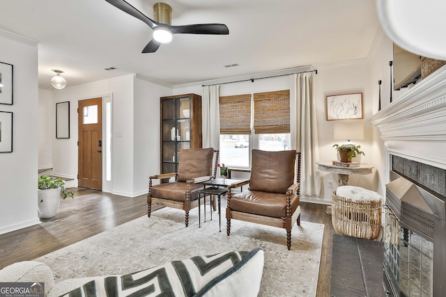 living area with crown molding, dark hardwood / wood-style floors, and ceiling fan