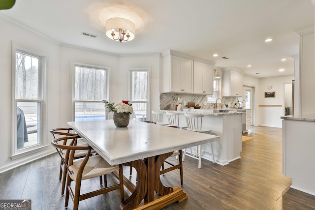 dining area featuring ornamental molding, plenty of natural light, dark wood-type flooring, and sink