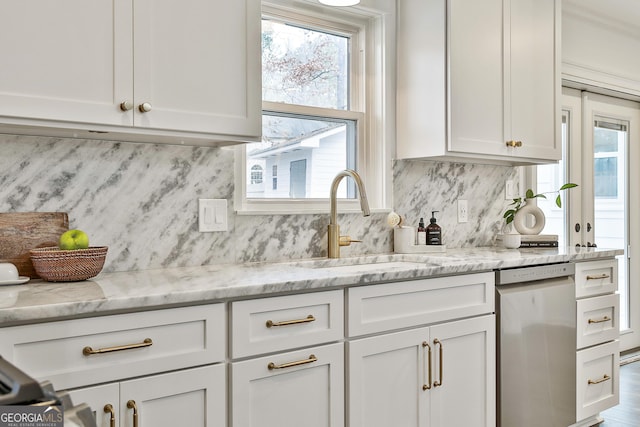 kitchen featuring light stone countertops, sink, stainless steel dishwasher, and white cabinets