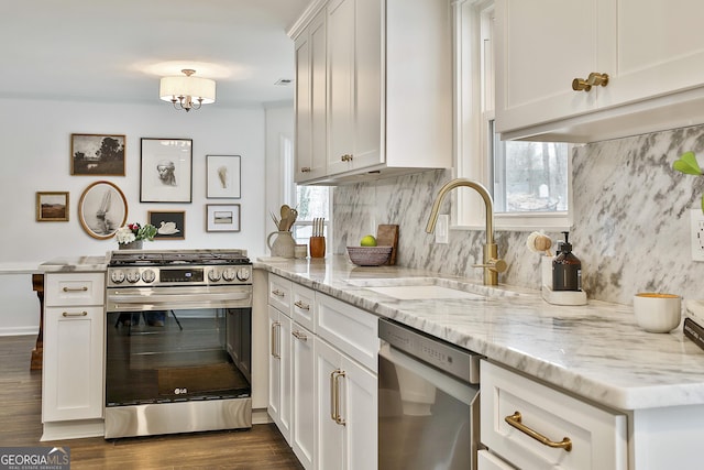 kitchen featuring stainless steel appliances, light stone countertops, sink, and white cabinets