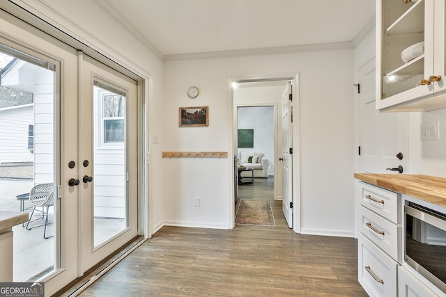 interior space featuring french doors, butcher block counters, crown molding, wood-type flooring, and white cabinets