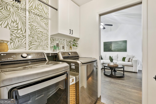 laundry area with light hardwood / wood-style floors, cabinets, and washing machine and clothes dryer