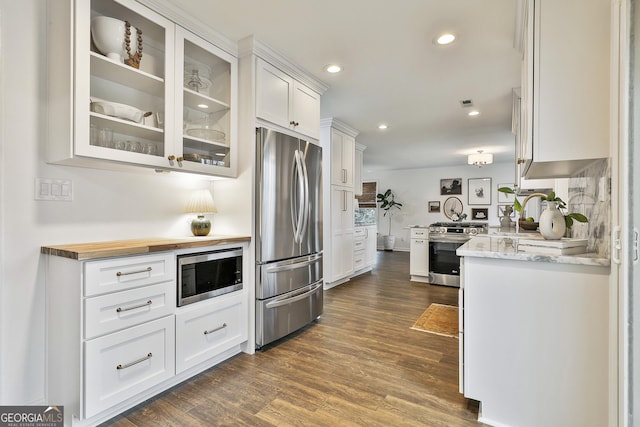 kitchen with dark wood-type flooring, sink, light stone counters, stainless steel appliances, and white cabinets