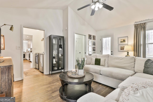 living room featuring washer / clothes dryer, light hardwood / wood-style flooring, high vaulted ceiling, and ceiling fan