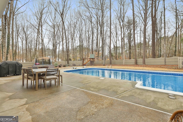 view of pool featuring a patio area, area for grilling, a diving board, a trampoline, and a playground