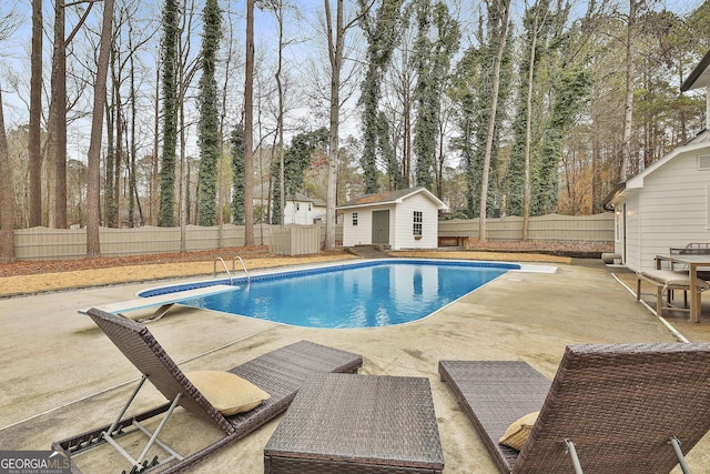 view of swimming pool featuring a diving board, an outdoor structure, and a patio area