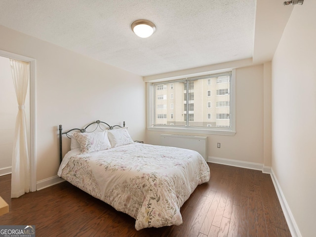 bedroom with dark wood-type flooring, radiator heating unit, and a textured ceiling