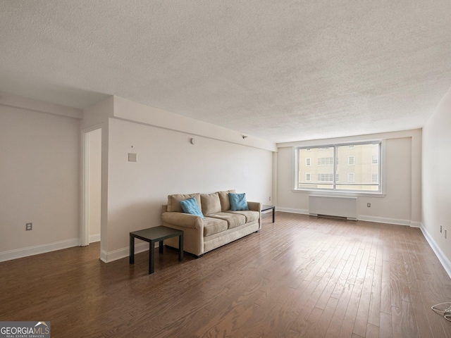 living room with dark wood-type flooring, radiator, and a textured ceiling