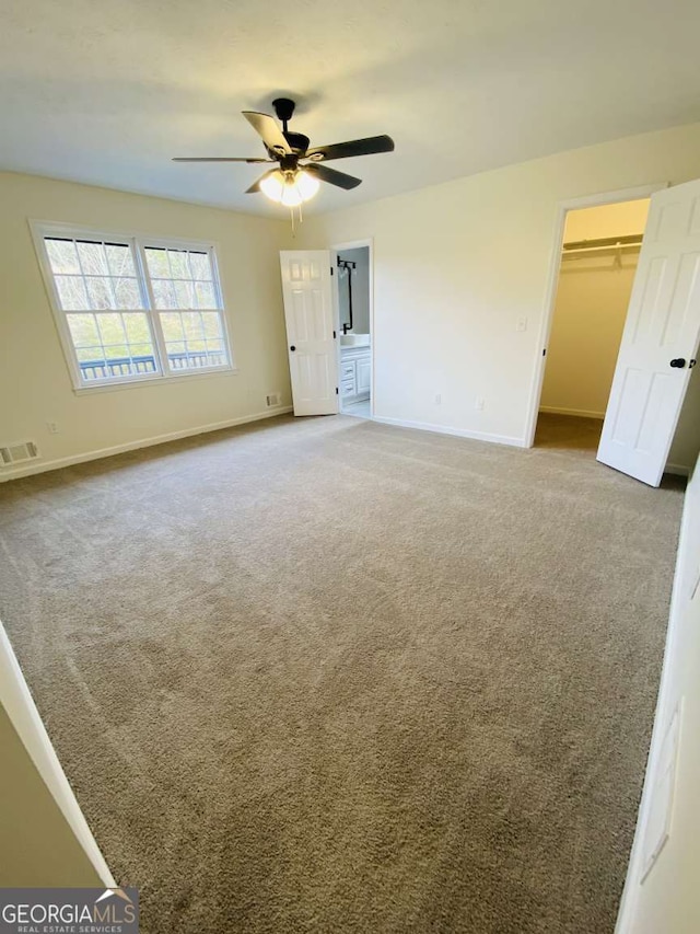 unfurnished bedroom featuring carpet, a spacious closet, and ceiling fan