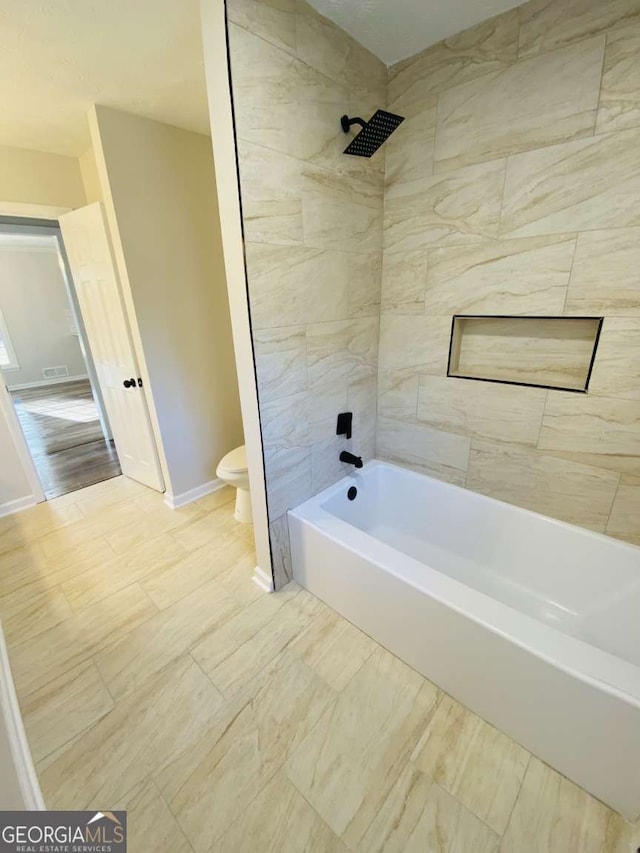 bathroom with tiled shower / bath and toilet