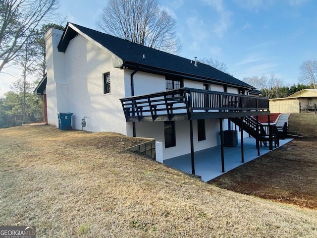 back of property with a wooden deck, a patio, and a lawn