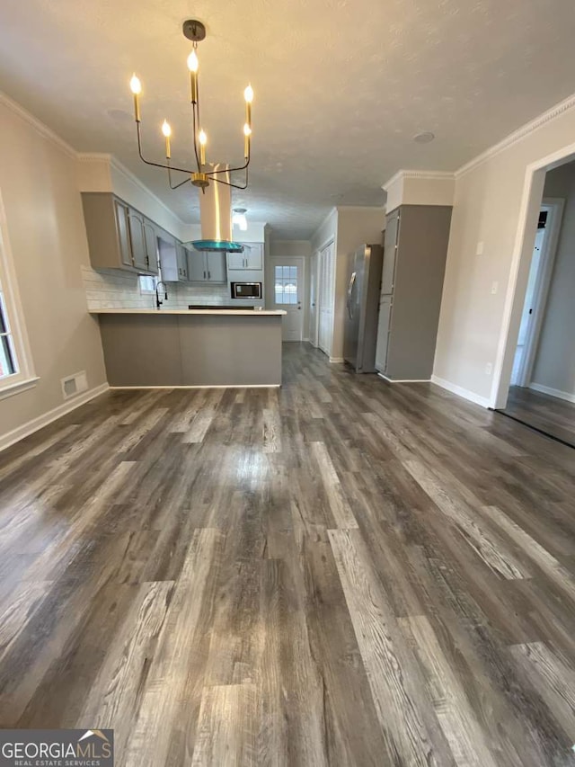 kitchen with decorative backsplash, ornamental molding, stainless steel appliances, and kitchen peninsula