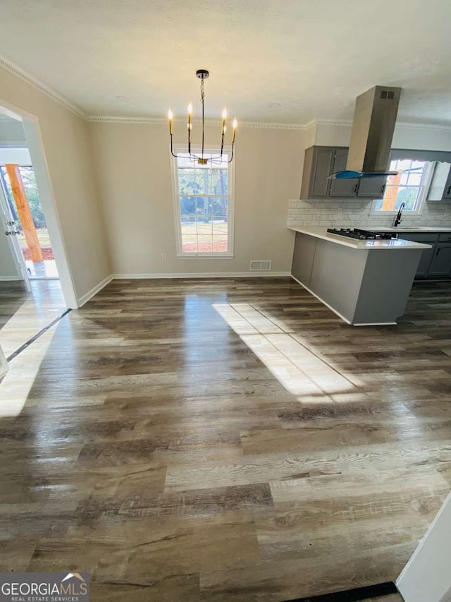 unfurnished dining area featuring an inviting chandelier, ornamental molding, and dark hardwood / wood-style floors