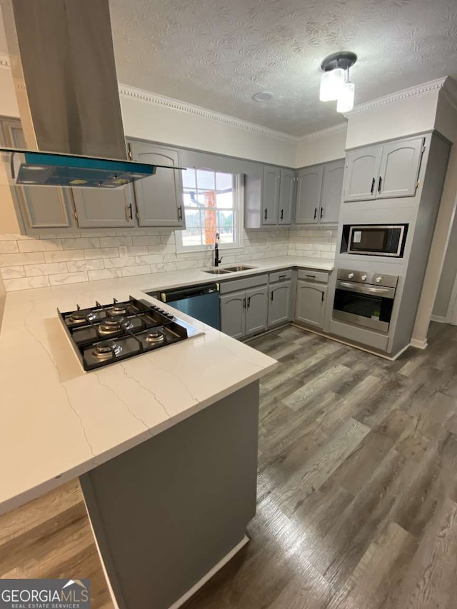 kitchen with black gas cooktop, sink, island exhaust hood, stainless steel oven, and kitchen peninsula