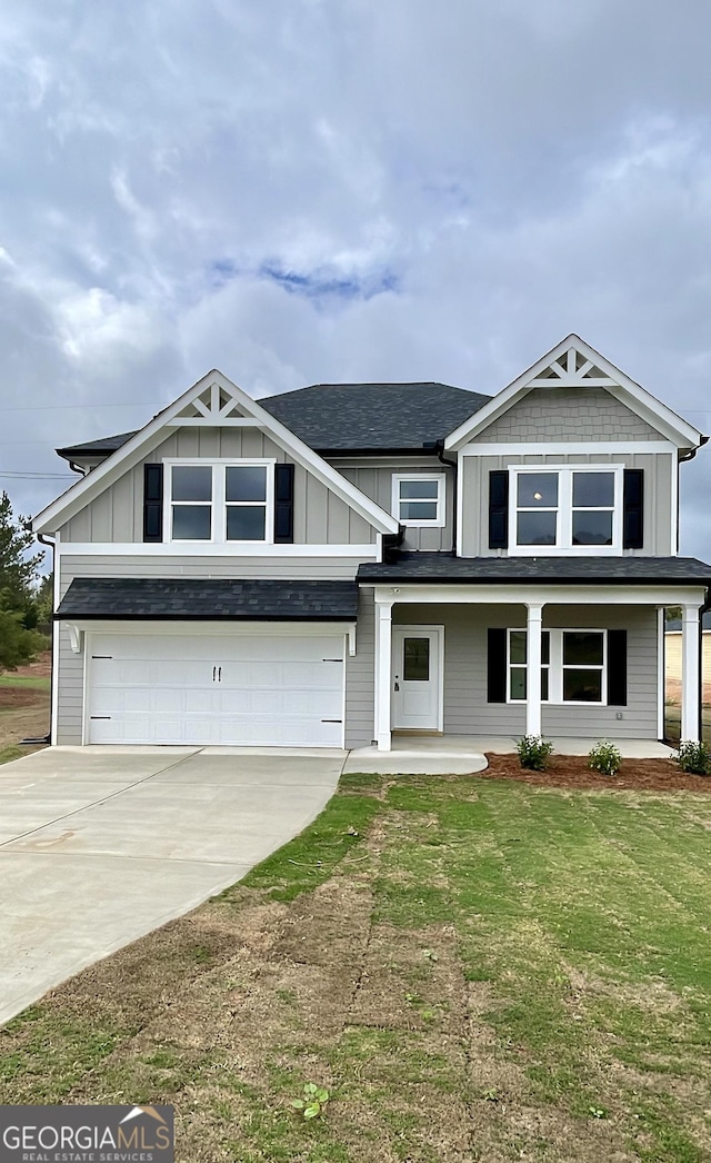 view of front of property with a porch, a garage, and a front lawn