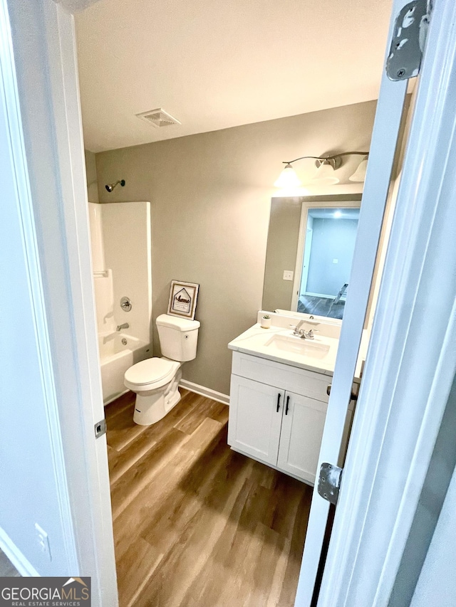 full bathroom with hardwood / wood-style flooring, vanity,  shower combination, and toilet