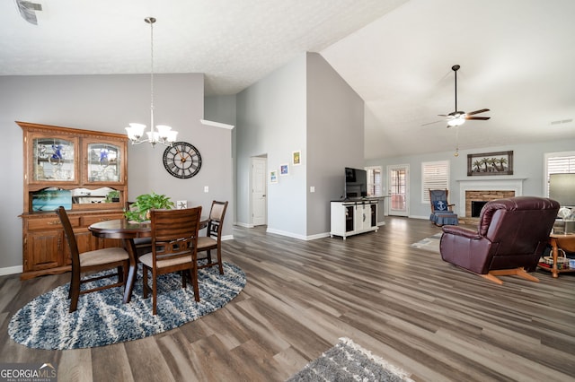 dining area featuring high vaulted ceiling, ceiling fan with notable chandelier, and dark hardwood / wood-style flooring