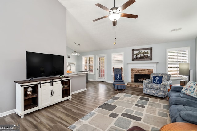 living room featuring high vaulted ceiling, dark wood-type flooring, ceiling fan with notable chandelier, and a fireplace